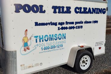 image of a trailer with Pool tile cleaning written on it. The trailer has a thomson pool tile cleaning logo on it